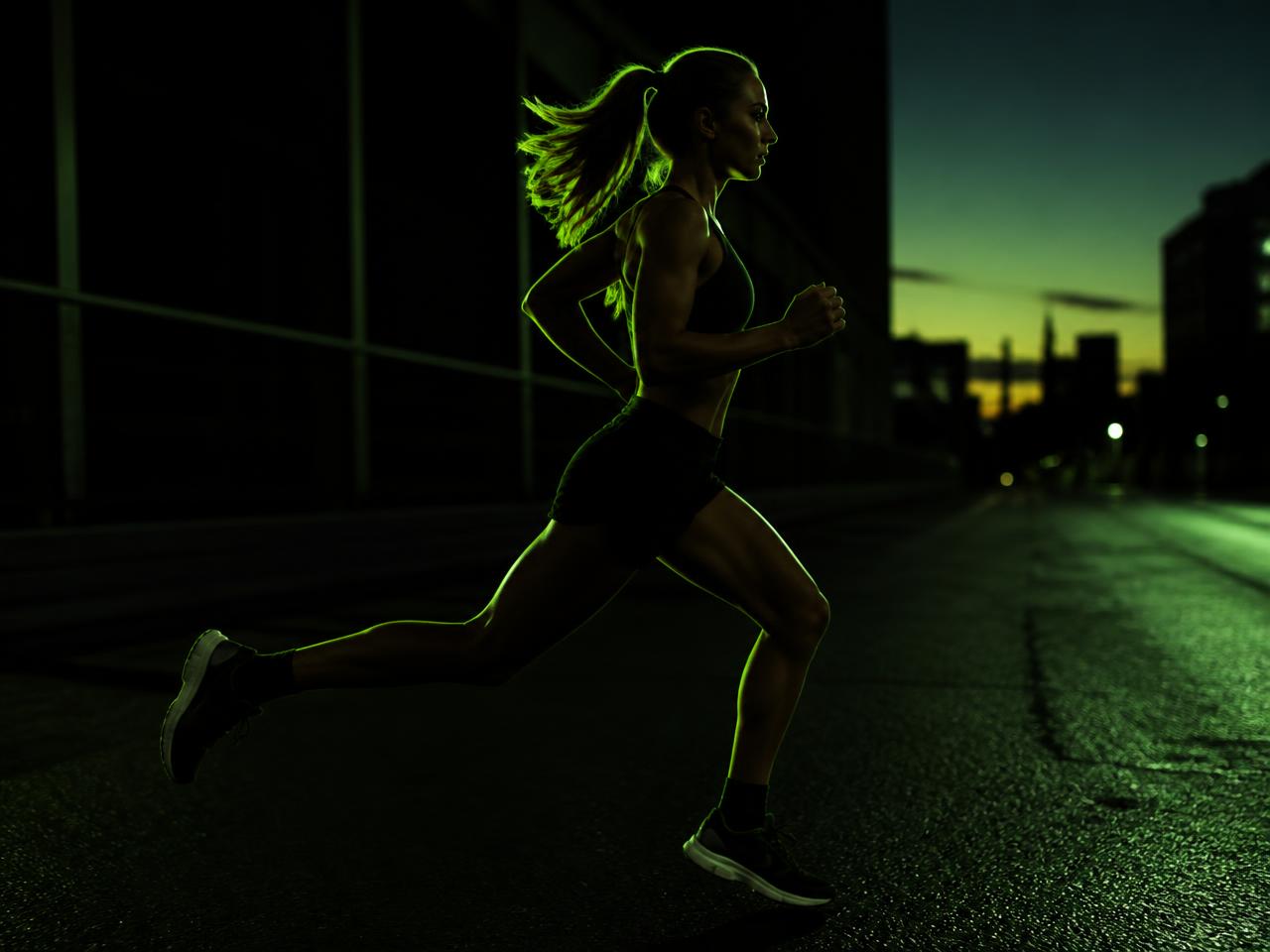 Runner training at dawn under green rim light